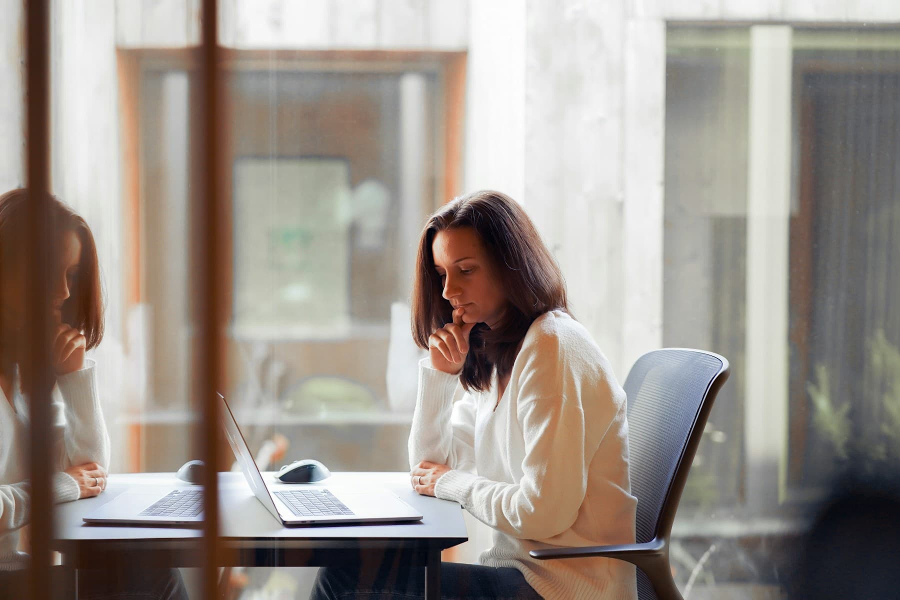 Woman reviewing a laptop screen beside a window